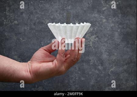 Tenir à la main le café filtre en papier blanc inutilisé dans Studio Banque D'Images