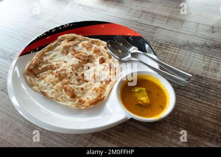 Gros plan du simple roti canai sans friture avec curry de dhal sur une table en bois Banque D'Images
