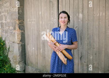 Jeune femme debout avec des baguettes françaises à la campagne Banque D'Images