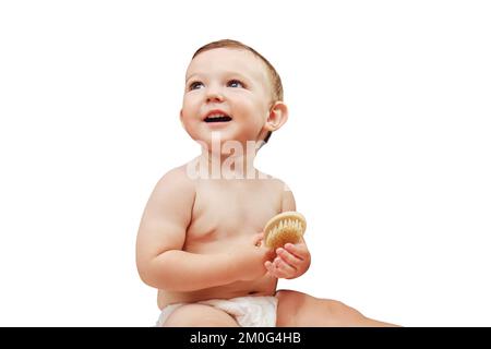 Portrait d'un bébé heureux avec un peigne dans la salle de bains près du miroir, isolé sur un fond blanc. Bébé garçon assis sur une serviette, isolé sur un Banque D'Images
