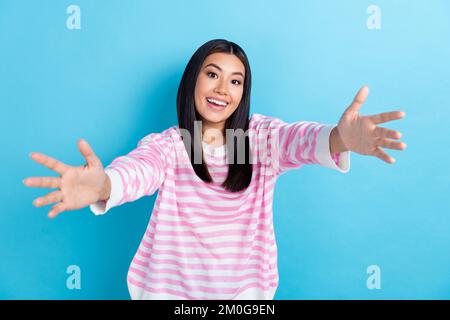 Photo de adorable jeune femme excitée porter chandail rayé bras ouverts prêt vous hug isolé couleur bleu fond Banque D'Images