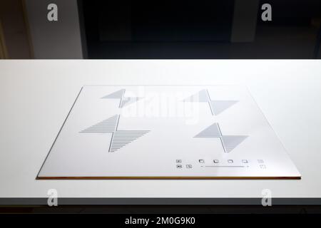 Comptoir blanc avec blanc beige brillant intégré céramique céramique induction ou cuisinière électrique avec quatre brûleurs dans la cuisine moderne vide sombre Banque D'Images