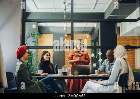 Des hommes d'affaires souriants sourient lors d'une réunion dans un bureau créatif. Groupe de professionnels d'affaires joyeux travaillant en équipe dans un multi Banque D'Images