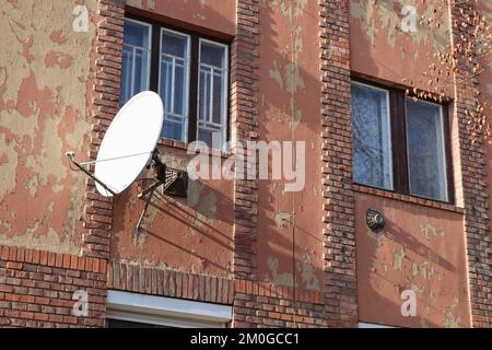 Plat satellite sur le mur d'un ancien immeuble d'appartements Banque D'Images