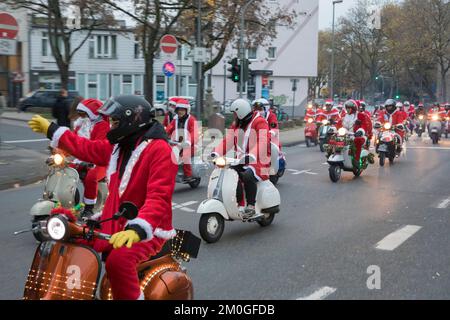 Les membres des clubs de scooter Vespa vêtus de Santas lors d'une promenade à travers la ville, Cologne, Allemagne. Les trottinettes sont illuminées et décorées pour le CHRI Banque D'Images