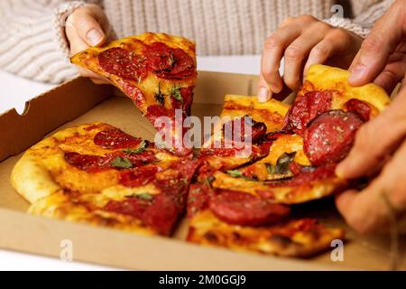 mains prenant des tranches de pizza de pepperoni de la boîte Banque D'Images