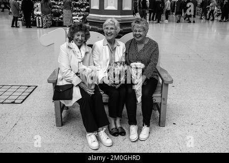 Un groupe de femmes séniors à Victoria Station avec des grappes de fleurs sur leur chemin vers Buckingham Palace après la mort de la Reine, Londres, Royaume-Uni. Banque D'Images