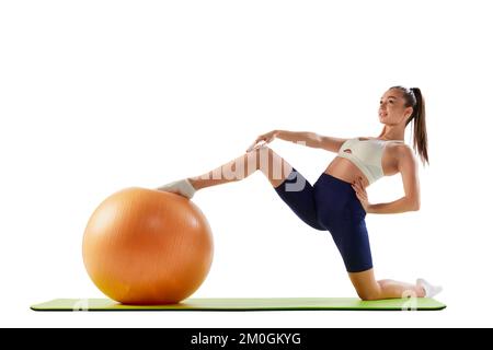 Portrait de la jeune femme sportive entraînement, faisant des exercices d'étirement avec le ballon de fitness en caoutchouc isolé sur fond blanc. Concept de sport Banque D'Images