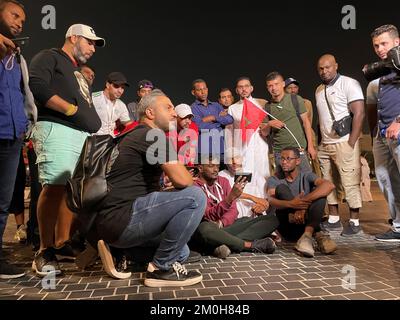 Les fans de football regardant le match Maroc / Espagne à l'extérieur du stade Education City, au Qatar, lors de la coupe du monde de la FIFA 2022. Il y avait des scènes tendues plus tôt à l'extérieur du stade, alors que la police anti-émeutes avait mis son casque, que la police montée et les chiens avançait et qu'au moins deux personnes ont été retirées par les forces de sécurité. Des dizaines de supporters marocains étaient à l'extérieur du stade alors que leur équipe jouait en Espagne. Date de la photo: Mardi 6 décembre 2022. Banque D'Images