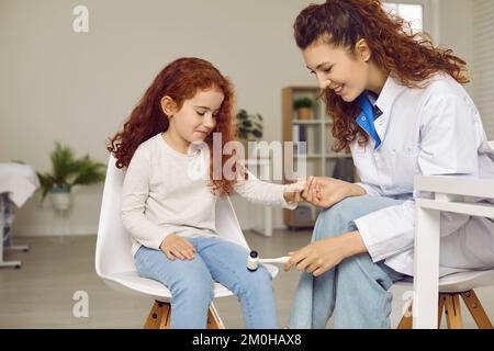 Neurologue pédiatrique examinant le petit enfant heureux et utilisant un marteau pour tester le réflexe du genou Banque D'Images