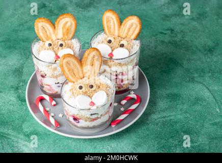 Gâteau sans cuisson sous forme de lapins mignons dans des verres avec des cerises, des biscuits et de la crème caillé. Symbole de la nouvelle année 2023 Banque D'Images