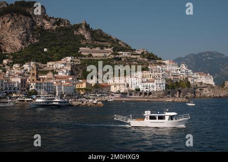 Vue générale de la ville d'Amalfi depuis la marina, en direction de la ville principale avec Battellieri Amalfi en premier plan et falaises pittoresques en arrière-plan. Banque D'Images