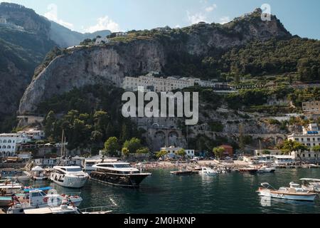 Vue sur les falaises de calcaire et le Grand Hotel Convento di Amalfi surplombant la ville d'Amalfi avec la marina et les yachts à moteur de luxe en premier plan Banque D'Images