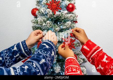 Couple décorant arbre de Noël tout en préparant pour les vacances à la maison. Banque D'Images
