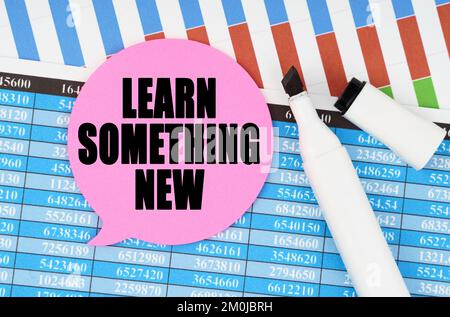 Concept économique et commercial. Sur les États financiers et les graphiques, il y a un marqueur et un autocollant avec l'inscription - APPRENDRE QUELQUE CHOSE DE NOUVEAU Banque D'Images