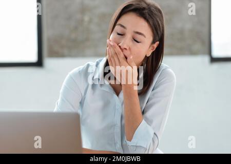 Les bâches de travail de bureau de femme couvrent la bouche le concept de privation chronique de sommeil surtravail Banque D'Images