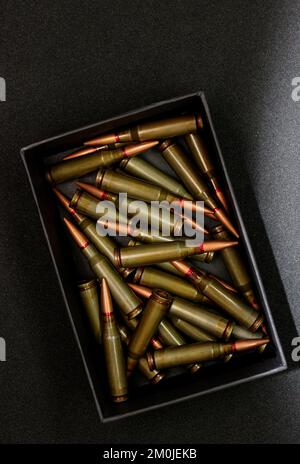 Munitions vivantes pour fusil d'assaut dans une boîte en carton noir sur fond noir Banque D'Images