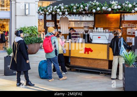 Jeunes étudiants en file d'attente pour être servi avec du café.Server prend le paiement pendant que d'autres attendent.Une ombre de lumière de la gauche dans une image nette Banque D'Images