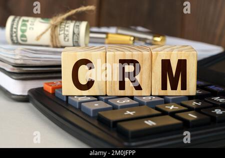 Concept de finance et d'économie. Sur la table sont de l'argent, une calculatrice, un bloc-notes et des cubes avec l'inscription - CRM Banque D'Images