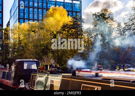 Bateaux-canaux amarrés sur le canal à King's Cross.deux bateaux-canaux photographiés avec un fort éclairage latéral.un bateau a leur cheminée cheminée fume . Banque D'Images