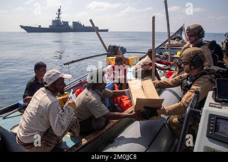 Golfe d'Aden. 29th novembre 2022. Les marins du destroyer à missiles guidés USS Nitze (DDG 94) donnent des collations, de l'eau et d'autres fournitures dans une boîte aux civils à bord d'un bateau à moteur dans le golfe d'Aden, en novembre. 29. Nitze est déployé dans la zone d'opérations de la flotte américaine 5th afin d'assurer la sécurité et la stabilité maritimes dans la région du Moyen-Orient. Crédit : États-Unis Marine/ZUMA Press Wire Service/ZUMAPRESS.com/Alamy Live News Banque D'Images