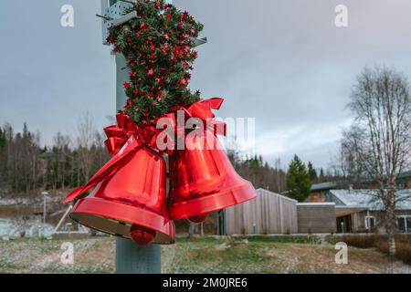 Deux grands cloches rouges de Noël avec noeud rouge et feuilles de pin, décoration de Noël de rue, arrière-plan flou Banque D'Images