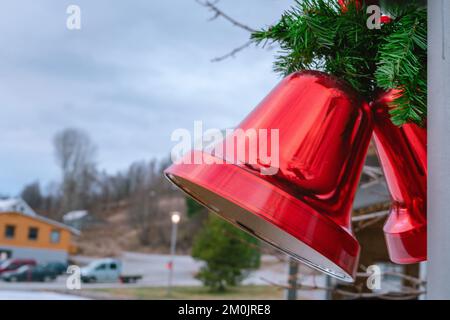 Deux grands cloches rouges de Noël avec noeud rouge et feuilles de pin, décoration de Noël de rue, vue rapprochée du côté droit, arrière-plan flou Banque D'Images