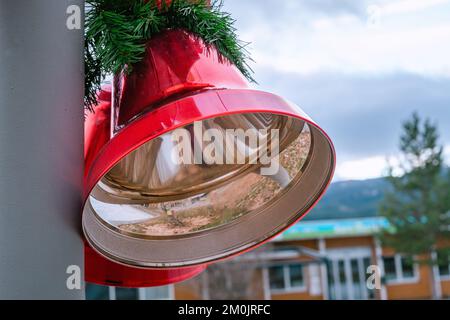 Deux grands cloches rouges de Noël avec noeud rouge et feuilles de pin, décoration de Noël de rue, vue rapprochée du côté gauche, arrière-plan flou Banque D'Images