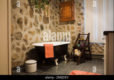 Baignoire avec pied à griffe noir et blanc et mobilier ancien dans la salle de bains à l'intérieur d'une réplique de l'ancienne maison de style cottage Canadiana en bois et pierre de champ. Banque D'Images