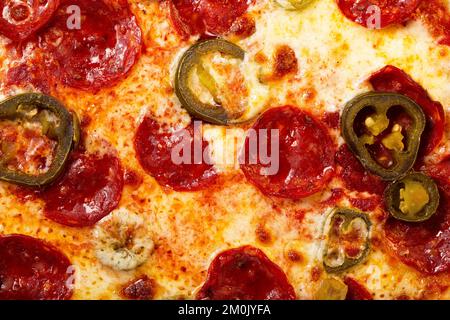 Texture de la pizza au salami pepperoni avec jalapeno comme fond. Un gros plan d'une pizza. Photo macro. Pizza au salami pepperoni avec jalapenos. Banque D'Images