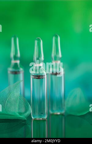 Sérum de mésothérapie et de dermabrasion en ampoules. Ampoules cosmétiques.produit de beauté.ampoules transparentes et feuilles vertes squelettes sur un turquoise Banque D'Images