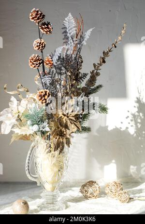 Un bouquet d'hiver chatoyant séché dans un vase en verre contre une fenêtre lumineuse et ensoleillée. Banque D'Images