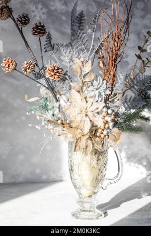 Un bouquet d'hiver chatoyant dans un vase en verre avec lumière du soleil vive. Banque D'Images