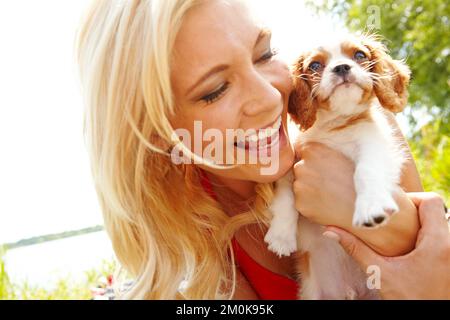 Ce chiot est parfait pour moi. une belle blonde tenant son chiot pendant qu'elle se tient dehors. Banque D'Images