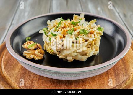 Salade de chicorée endive avec sauce Roquefort sur une assiette noire. Pose à plat. Banque D'Images