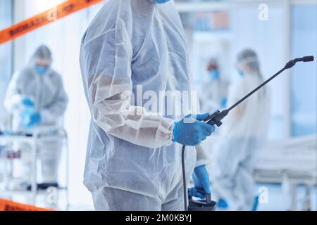 Gros plan sur la main du nettoyant pour déchets biologiques dangereux contenant l'équipement antiseptique. un membre csi nettoie une chambre d'hôpital. La biochimiste stérilise la salle de quarantaine des covidés Banque D'Images