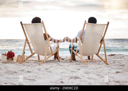 Vision d'un couple afro-américain passant une journée en mer ensemble. Contenu petit ami et petite amie tenant les mains tout en étant assis sur la plage Banque D'Images