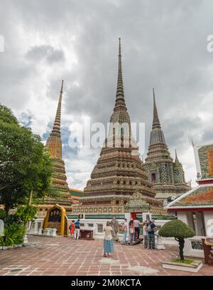 Un groupe de touristes visitant le temple bouddhiste de Wat Phra Chetuphon par temps nuageux Banque D'Images