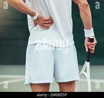 Joueur de tennis de course mixte inconnu de la vue arrière souffrant de mal de dos dans le jeu de court. Hispanique FIT athlète dans la douleur tout en tenant et frottant contre la blessure de dos dans Banque D'Images