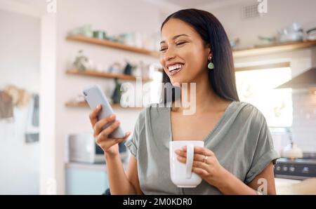 Jeune femme hispanique de race mixte utilisant un téléphone et de boire du café le matin à la maison. Jeune femme souriant en utilisant les médias sociaux ou en envoyant un Banque D'Images