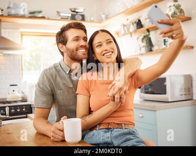 Jeune couple interracial joyeux prenant un selfie avec un téléphone ensemble à la maison. Joyeux petit ami caucasien et petite amie de race mixte prenant une photo Banque D'Images