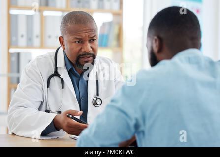 Médecin sérieux ayant une consultation avec un patient. Médecin parlant à un patient de ses résultats. Patient afro-américain parlant à son médecin Banque D'Images