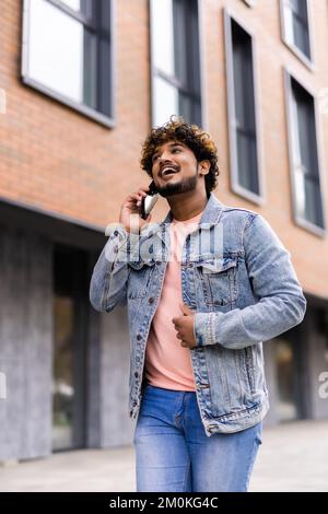 Beau jeune homme habillé de désinvolture passer du temps à l'extérieur de la ville, à l'aide de téléphone mobile tout en descendant des escaliers Banque D'Images