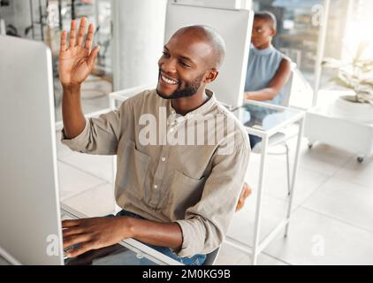 Un jeune homme d'affaires afro-américain agite lors d'un appel vidéo en utilisant un ordinateur de bureau dans un bureau au travail. Homme d'affaires heureux parlant et Banque D'Images