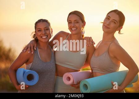 Portrait des femmes de yoga liant, tenant des tapis de yoga en pratique en plein air dans la nature éloignée. Groupe diversifié de jeunes amis actifs souriants debout Banque D'Images