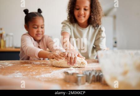 Deux sœurs de race mixte se sont amusées tout en cuisant ensemble à la maison. Les enfants ne sont joueurs que lorsqu'ils apprennent à cuisiner dans une cuisine Banque D'Images