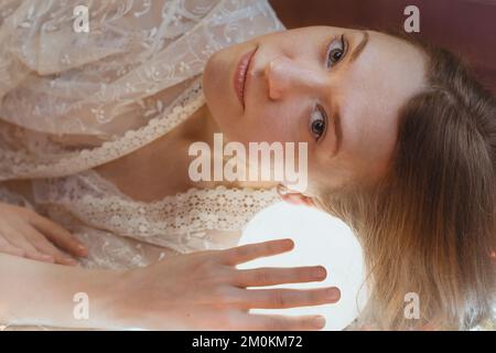 Gros plan une femme qui pose la tête sur une lampe à boule lumineuse portrait photo Banque D'Images
