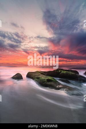 Une longue exposition verticale de pierres sous la vue spectaculaire des nuages roses de coucher de soleil Banque D'Images