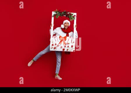 Pleine taille photo du corps de l'atmosphère d'hiver concept jeune gars tenir papier cadre ornement décor xmas Vibe portrait isolé sur fond rouge couleur Banque D'Images