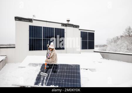 Femme nettoie les panneaux solaires de la neige Banque D'Images